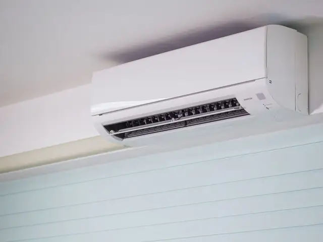 Ductless mini-split indoor unit mounted high on a bedroom wall