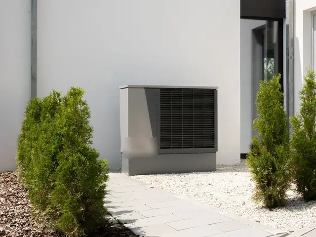 Modern air-source heat pump outdoor unit beside a house